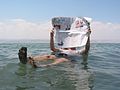 Turist citind un ziar în apa Mării Moarte