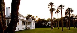 Photo of a sunset over a lawn featuring a large wooded area in the background