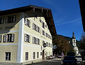 Gasthof Oberwirt mit der Kirche St. Sebastian im Hintergrund