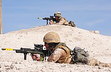 photographie en couleur montrant des soldats couchés dans le sable