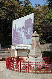 Photographie d'un monument en pierre et d'un grand panneau routier montrant une photo de camions.