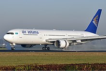 Un avion avec le fuselage blanc et la dérive bleue en train de rouler sur la piste. De la fumée s'échappe des réacteurs, les inverseurs de poussée et les volets sont déployés.