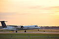 Un avion de Porter, au décollage sur la piste 06R-24L lors du coucher du soleil.