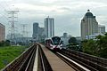 Tampak kereta Rute Kelana Jaya dengan latar belakang sebuah bangunan yang terletak di stasiun LRT Asia Jaya.