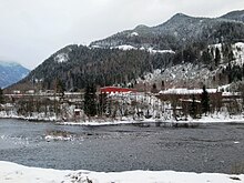 Foto eines Flusses in schneebedeckter hügliger Landschaft