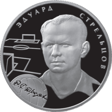 A silver coin with Strelstov's head and neck illustrated in relief upon it, accompanied by the outlines of a football pitch and a football and his name in Russian.