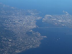 Aerial view of Metro Cebu in 2023. To the left are Cebu City, Mandaue, and Talisay. To the right is Mactan.