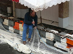 Un pêqueu (pêcheur) ravaudant ses filets près du funiculaire.