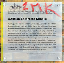 Farbfotografie von einer Tafel an einer Hauswand mit dem Titel „Aktion Entartete Kunst“. Das Aktive Museum Berlin erläutert das Depot mit entarteter Kunst aus den Jahren 1937 bis 1939.