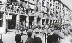 1941年12月28日，日軍先後在九龍及香港島舉行入城式，陸軍第23軍司令酒井隆（左二）及海軍第二遣支艦隊司令新見政一（左一）在軒尼詩道策馬檢閱侵港日軍，並向在路旁列隊的日軍士兵敬禮。