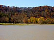 A lake with a forested mountain ridge in the background during autumn.