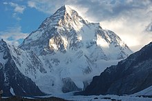 Montagne enneigée illuminée par endroits par le soleil.