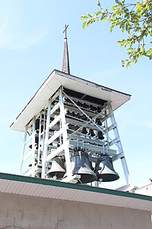 A steel structure containing 56 hanging bells of various sizes and topped with a roof spire and a cross