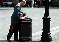 Man searching a London rubbish bin for food.