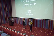 תרגום בשפת הסימנים הישראלית במפגש ויקיפדיה העברית בסינמה סיטי בירושלים, 11 בינואר 2019. מימין לשמאל: מיכל לסטר, מנכ"לית ויקימדיה ישראל; מתורגמנית; איציק אדרי, יו"ר ויקימדיה ישראל.