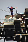 An individual dressed as Superman bungee jumping