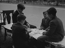 Photographie d'enfant assis dans la rue autour d'un jeu de cartes.