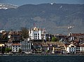 Nyon dan Kastil Putih yang terlihat dari danau selama musim semi, dengan Pegunungan Jura di belakang