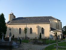 Vue latérale de la nef d'une église ; cimetière au premier plan.