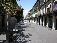 Rua principal de Alcalá de Henares. Os pórticos são uma estrutura singular e característica do urbanismo espanhol. Nesse caso, trazem para o seu interior curiosos elementos da antiga juderia da cidade como são os adarves, em contraste com seu traçado retilíneo (sobre o caminho preexistente, conecta o antigo centro romano com a praça, que de forma característica surgiu em um subúrbio).