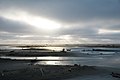 Sandy beach with sunbeams peeking through overcast sky