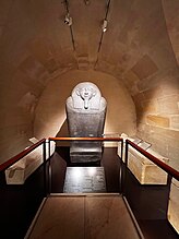 Photograph of the sarcophagus surrounded by other Phoenician objects in the Louvre