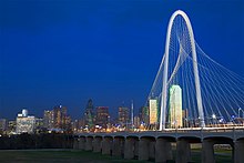 Photo de nuit d'un pont au-dessus du fleuve Trinity et des bâtiments de la ville de Dallas, dans le fond