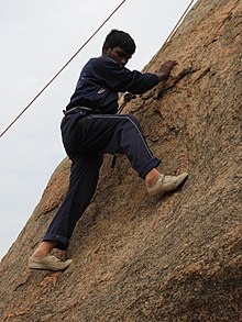 Ein Mann mit Klettergurt an einer Felswand