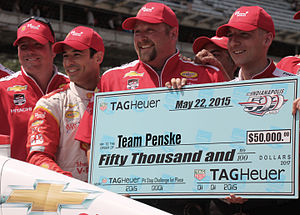 Crew members employed by Team Penske holding a large cheque for $50,000