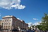 Grand city building below beautiful blue sky and clouds