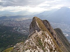 Arêtes rocheuses dominant une agglomération en arrière-plan.