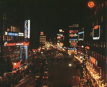 Kungsgatan i julbelysning 1965 och 2010 med vy västerut från Malmskillnadsbron. Längst till höger syns fasaden för Centrumhuset, ritad av Cyrillus Johansson och i bakgrunden hörnan av fastigheten Hästhuvudet 13. Till vänster skymtar biograf Royal där filmvisningen lades ner 2007. Utöver ljusreklamen har inte mycket förändrats; SF:s runda röda neonskylt fanns redan där på 1940-talet.