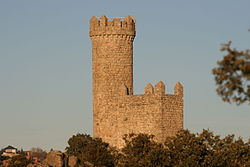 Small stone watchtower on a hill, with a clear blue sky on the background