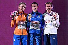 Diana van Es in orangener Jacke, Nadia Battocletti in blauer Jacke und Megan Keith in weißer Jacke, die Hosen sind jeweils blau.