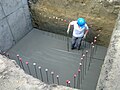 L'ouvrier tire la dalle à l'aide d'une barre pour béton auto-nivelant.