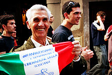 Smiling older man in a parade, holding a decorated Italian flag