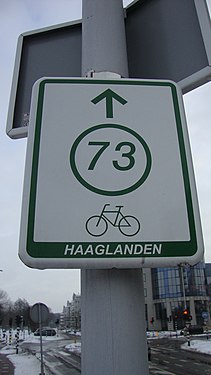 White sign with, in green, a circle containing the number "73", and an arrow