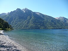 Vue du lac Gutiérrez. Ses rives sont recouvertes d'un beau manteau forestier. Il s'allonge du sud-sud-ouest vers le nord sur quelque 8 kilomètres, dans une vallée d'origine glaciaire entourée par les monts du Cerro Otto, du Cerro Catedral (2 405 mètres d'altitude) et du Cerro de la Ventana.