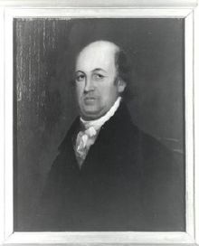 A balding man wearing a black jacket and white shirt