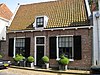 Laag huis onder zadeldak, rechte gootlijst. Poort