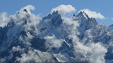 Trois groupes de pics acérés entourés de quelques nuages.