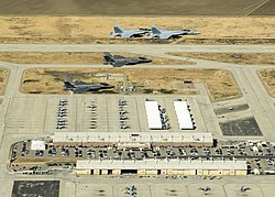 Flygfoto över basen från ett passagerarplan samt en bild med två par med F-35C Lightning II och F/A-18 Super Hornet flyger i formation över NAS Lemoore. Båda bilderna är tagna under 2015.