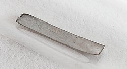 Thin gray sheet of metal, with a dull shine, encased in a glass tube