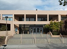 Two storey building constructed in beige-colored concrete with horizontal and rectangular windows