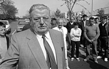 Photographie en noir et blanc d'un homme avec des lunettes, portant une cravate.