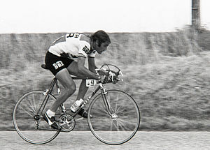 Photographie en noir et blanc, d'un homme faisant du vélo, comportant une plaque de cadre avec le numéro 41