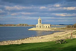 A lake with a rocky foreshore, and a small peninsula with a church built on it