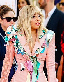 Lady Gaga in a colorful bodysuit looking to her left.