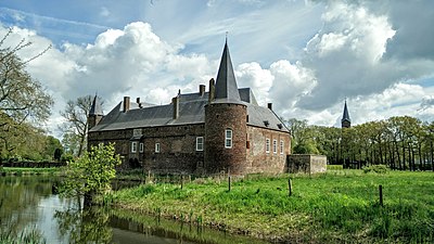 Een kasteel met slotgracht, op de achtergrond een kerktoren