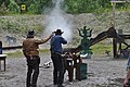 En Westernskytter avfyrer en bøylerifle mot stålmål. Til venstre står skyteleder med timer for å måle skytterens tid.